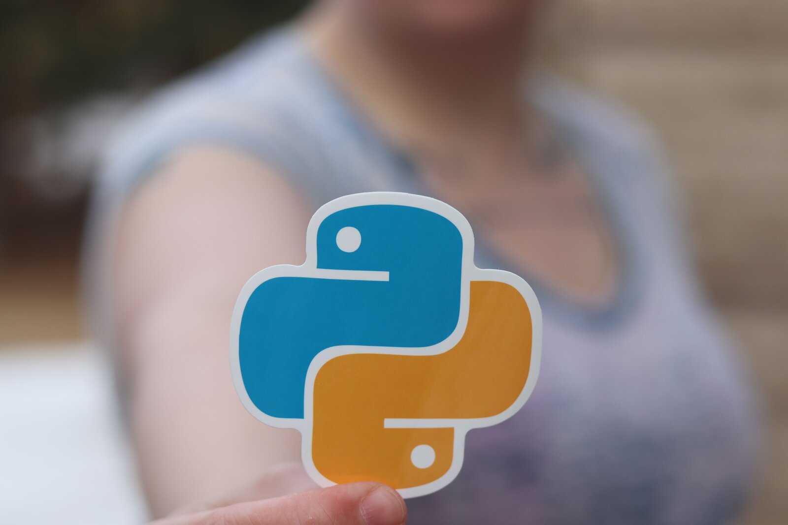 Naklejka loga języka python trzymana przez kobietę